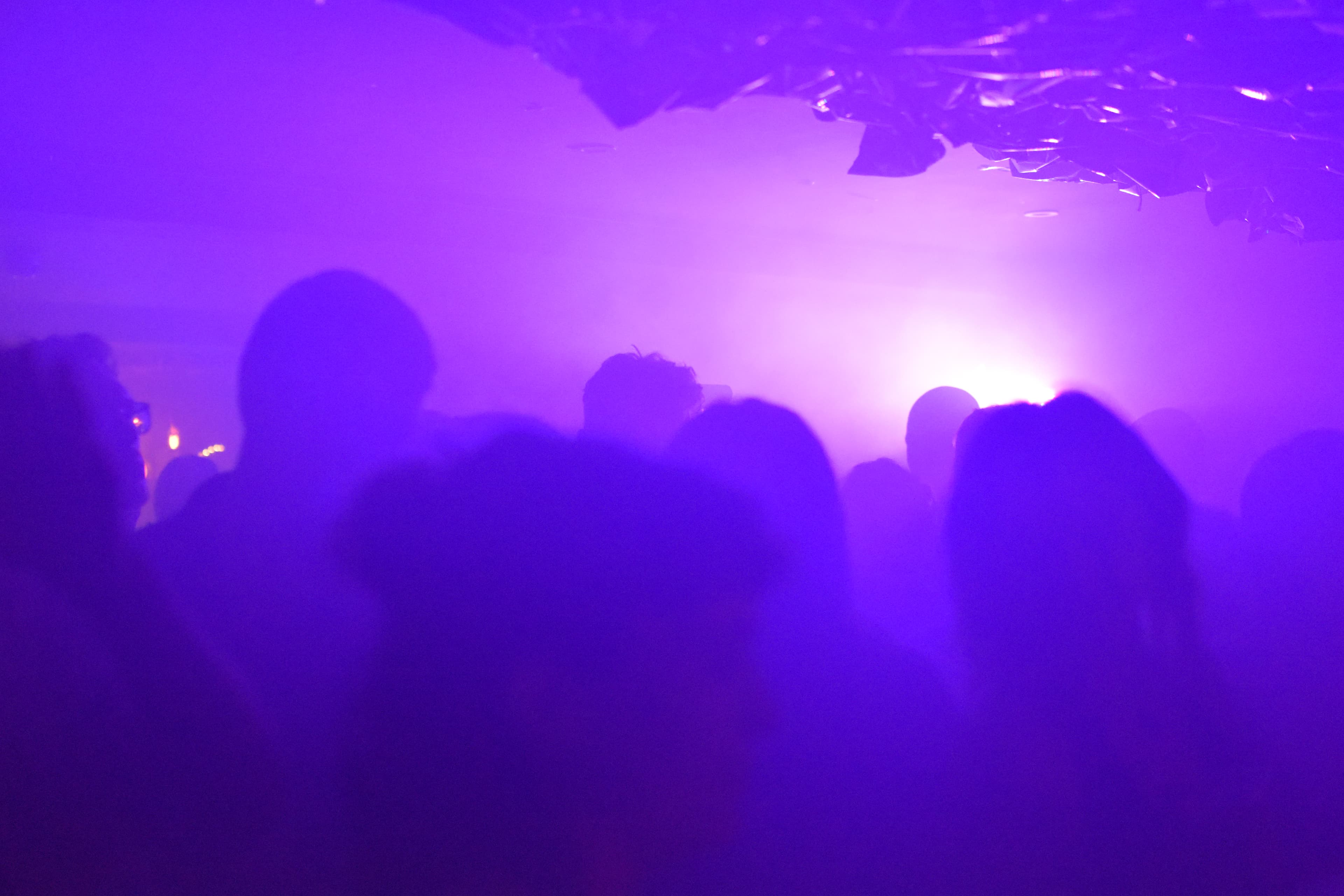 Heads in a smokey purple lit room